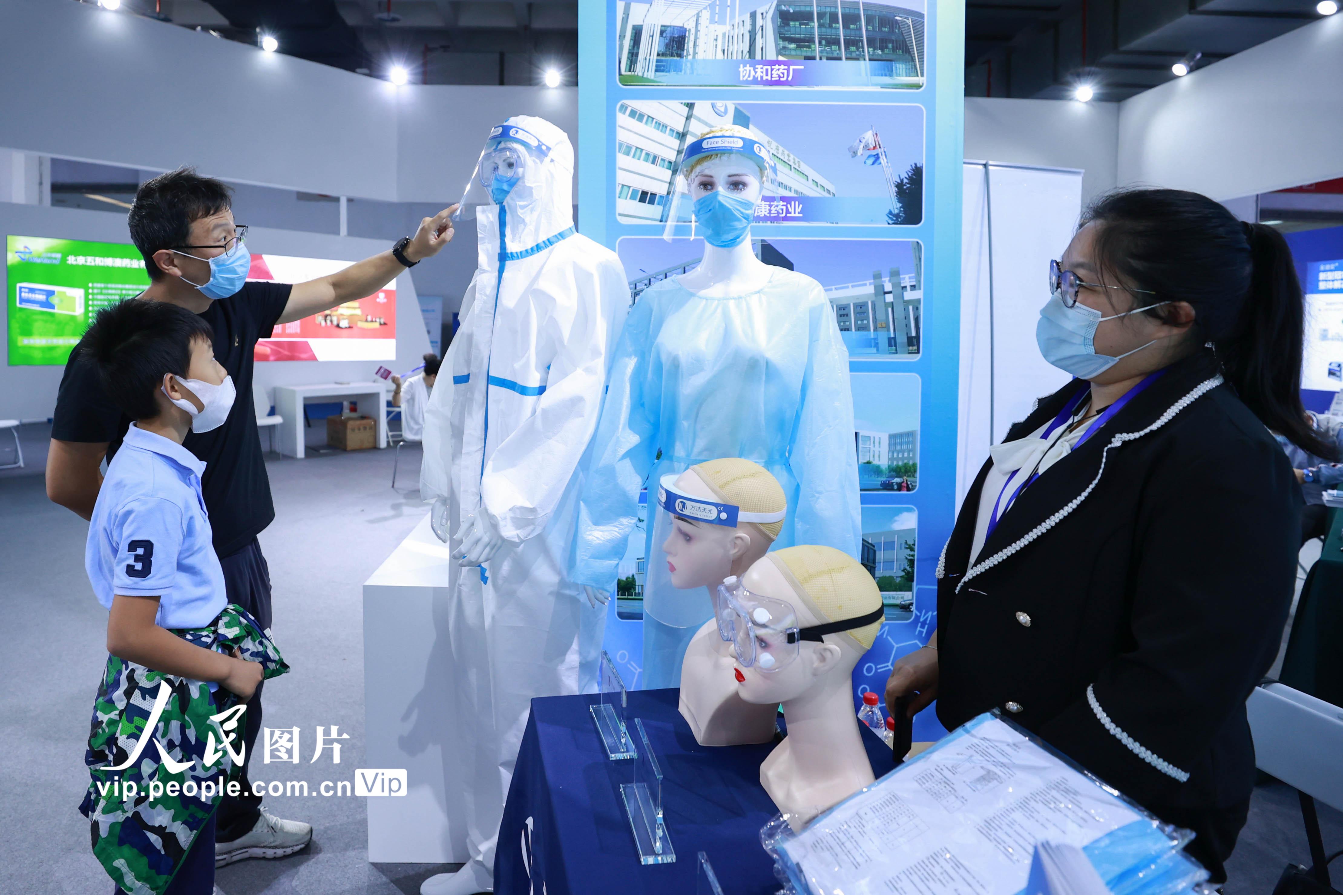 9月20日，家长在北京科博会上给孩子讲解医用防护产品。