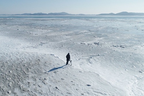 一名摄影师站在韩国首尔以西仁川东幕海滩结冰的海面上