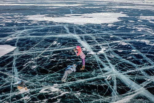 游客在贝加尔湖上洁净的冰上拍照