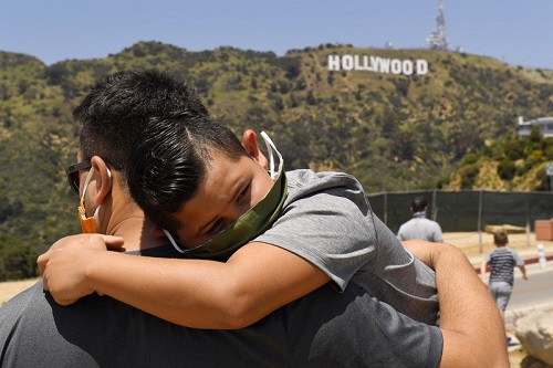 洛杉矶发生的冠状病毒爆发期间，一位父亲将他的儿子抱在着名的好莱坞标志附近