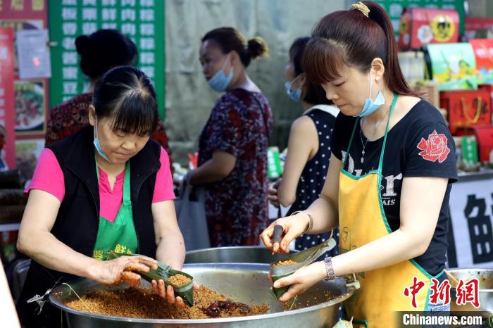 在街边支上一张小桌，放上一盆料，各个商家现场包粽子也一道“风景线”。　吕杨 摄