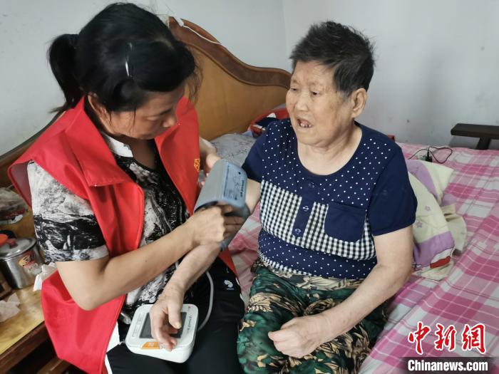 志愿者为老人李凤珍测量血压。　龚保兴 摄