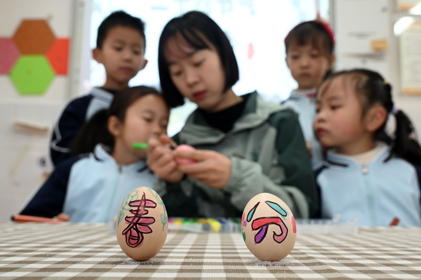 小朋友在老师带领下体验绘彩蛋和竖鸡蛋等传统习俗。兰自涛摄